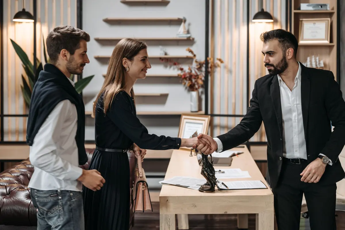Avocat accueillant un couple avec une poignée de main au cabinet