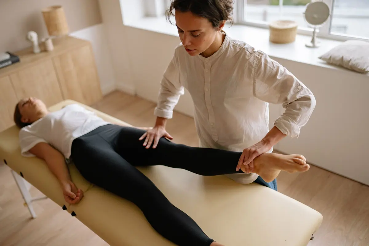 Kinésithérapeute mobilisant la jambe d'une patiente sur la table de soin