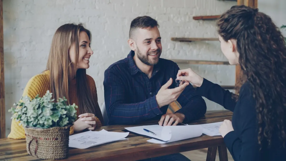 Couple heureux recevant les clés de son logement lors de la signature d'un achat immobilier