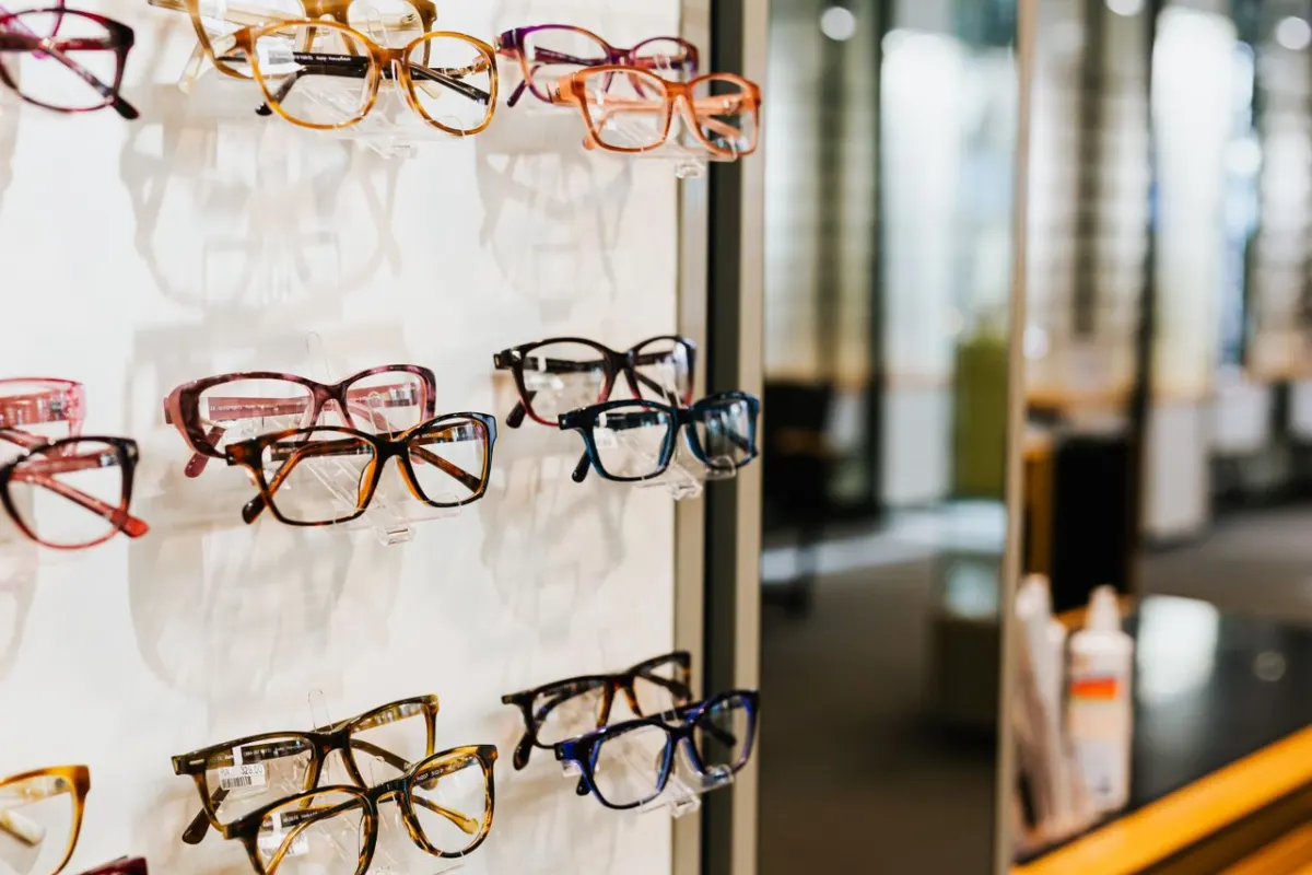 Montures de lunettes colorées présentées sur un mur dans une boutique d'optique soignée